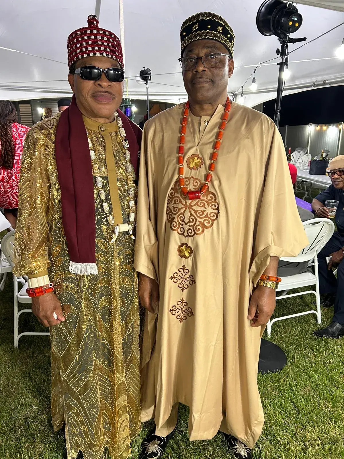 Two community members wearing ceremonial attire and coral beads