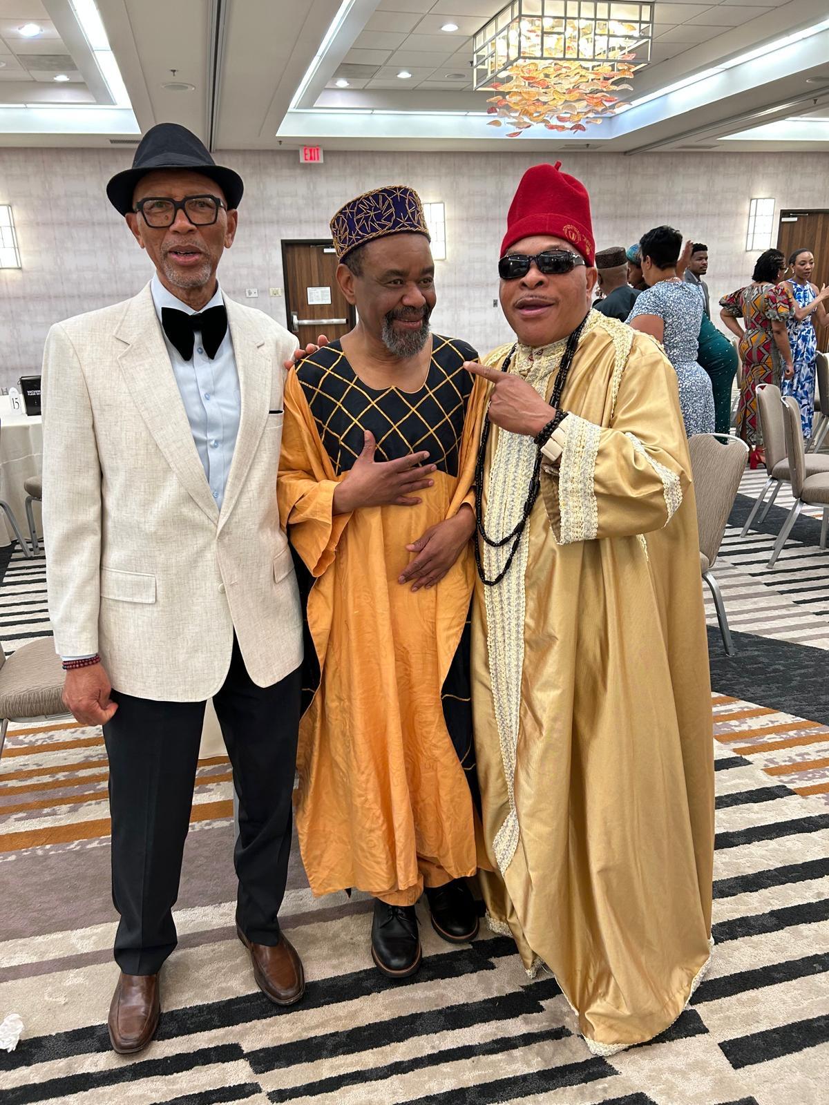 Three community members posing together in formal traditional attire