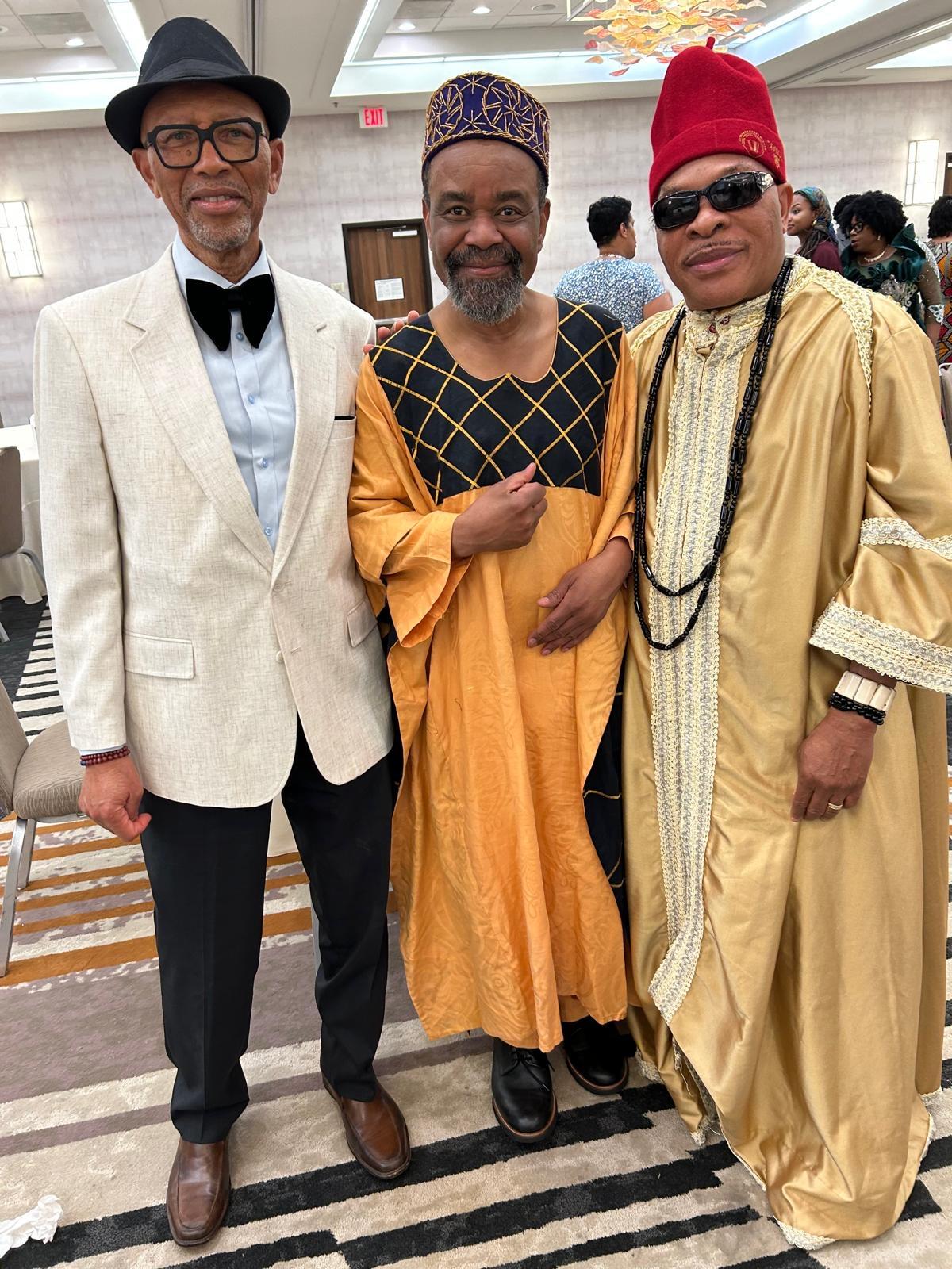 Three community members in traditional and formal attire