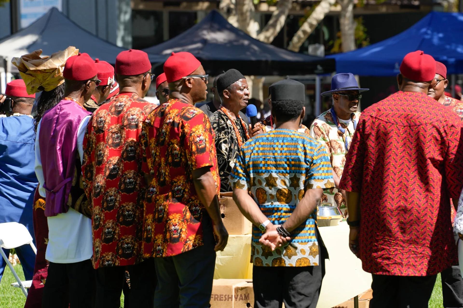 Community members in red traditional attire gathered beneath festival canopies
