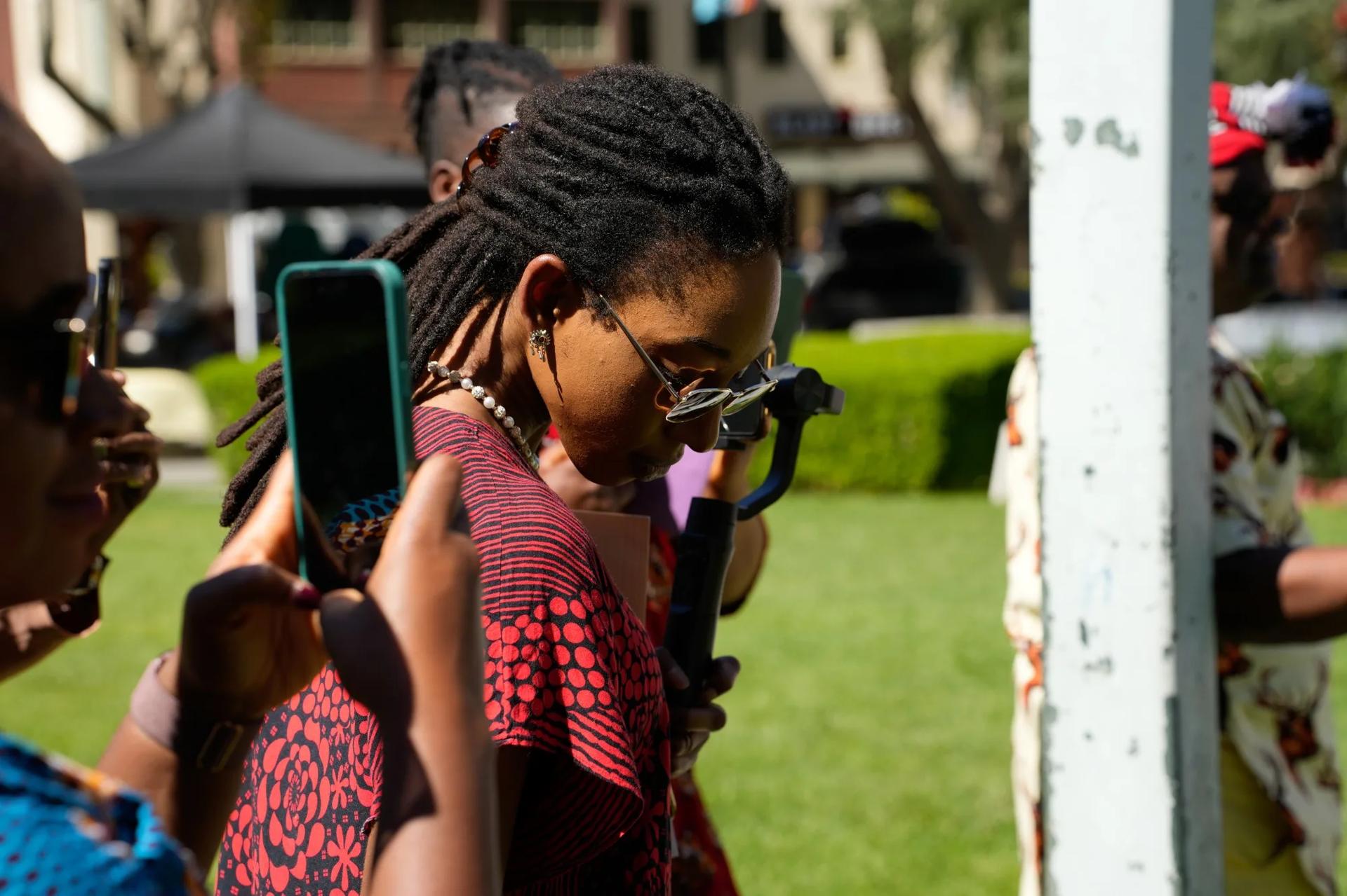 Young community member filming the festival on a phone gimbal