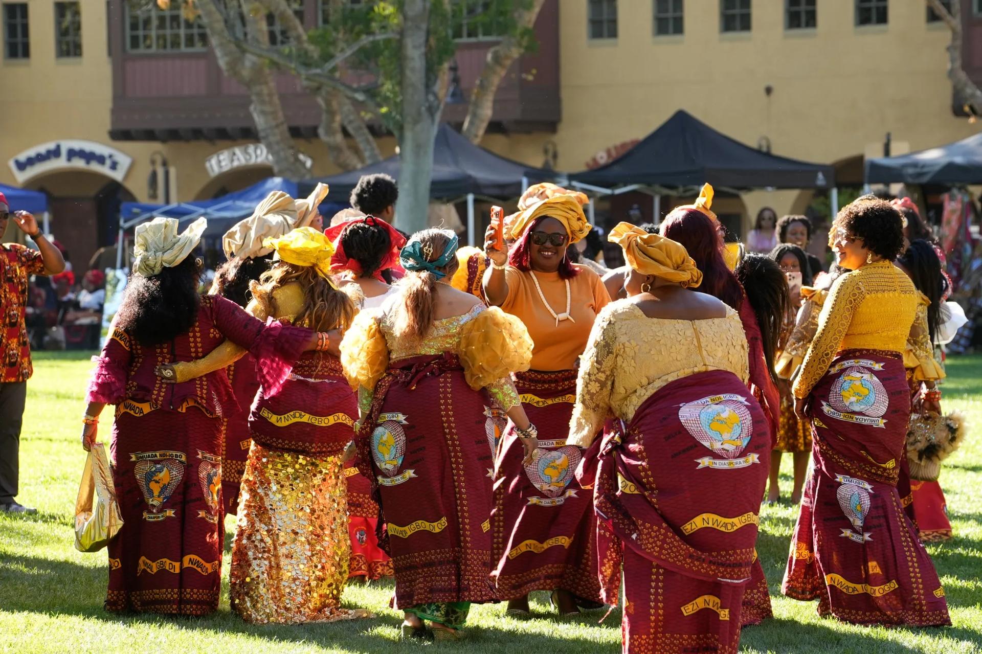 Umuada women dancing together in maroon and gold traditional attire